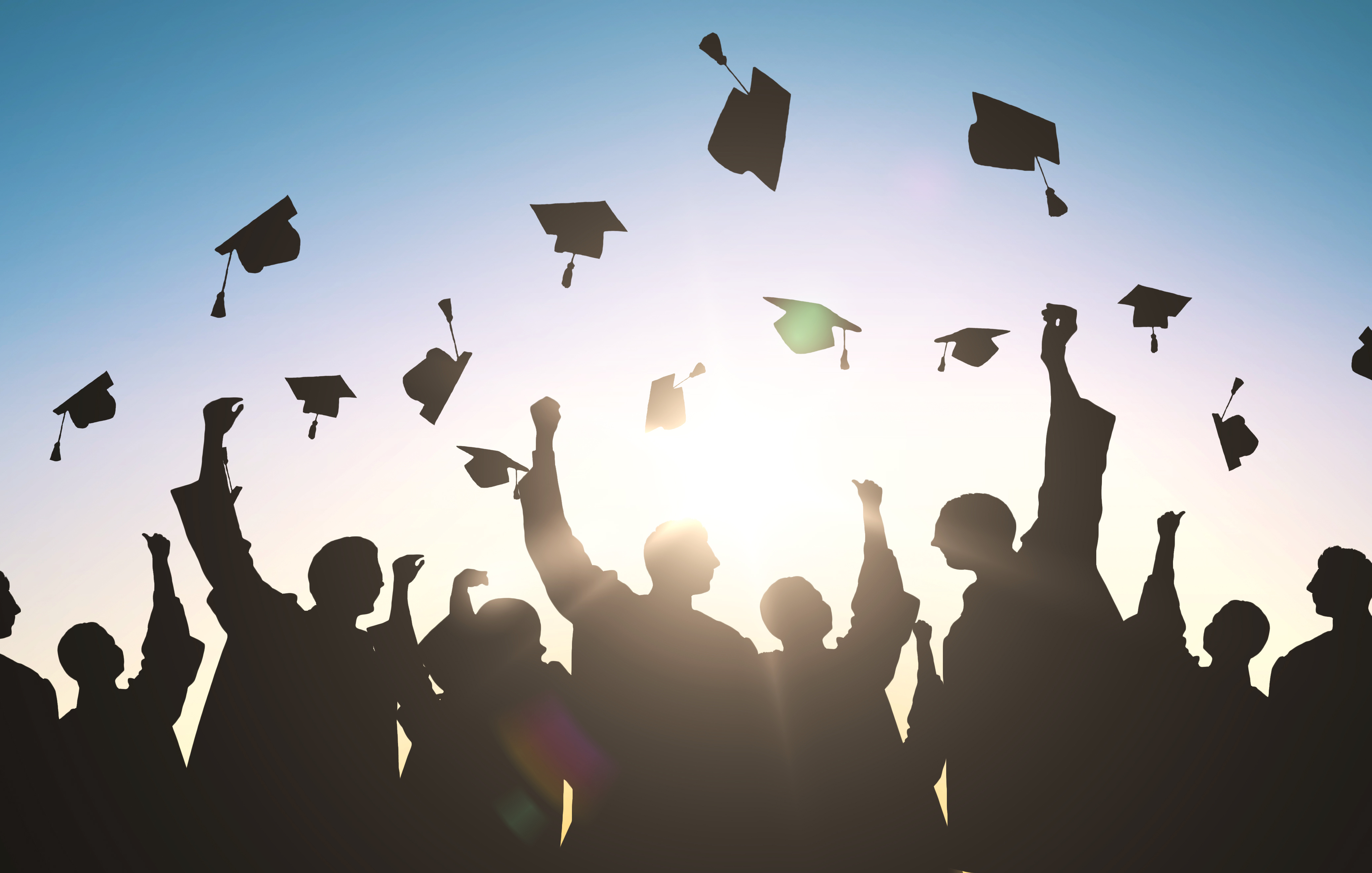 Students throwing graduation caps into sky