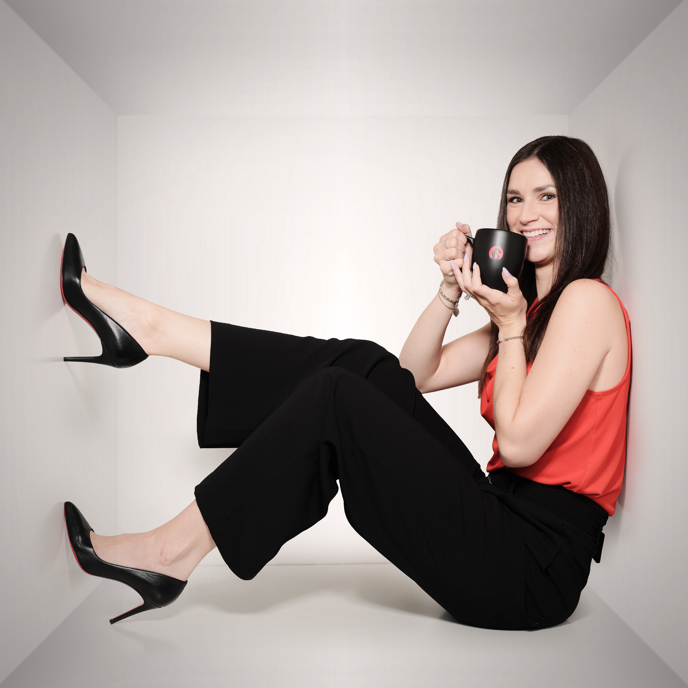 Bianca holding a coffee mug with feet kicked back on wall