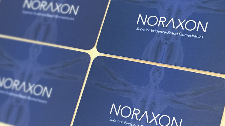 Close up of biomechanics manufacturer business card picturing an x-ray version of the Vitruvian Man and the company logo in white letters.