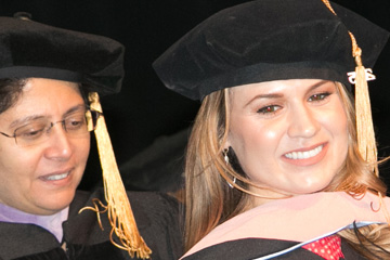 Image captured at a health sciences university graduation by FabCom of two women in cap and gown.
