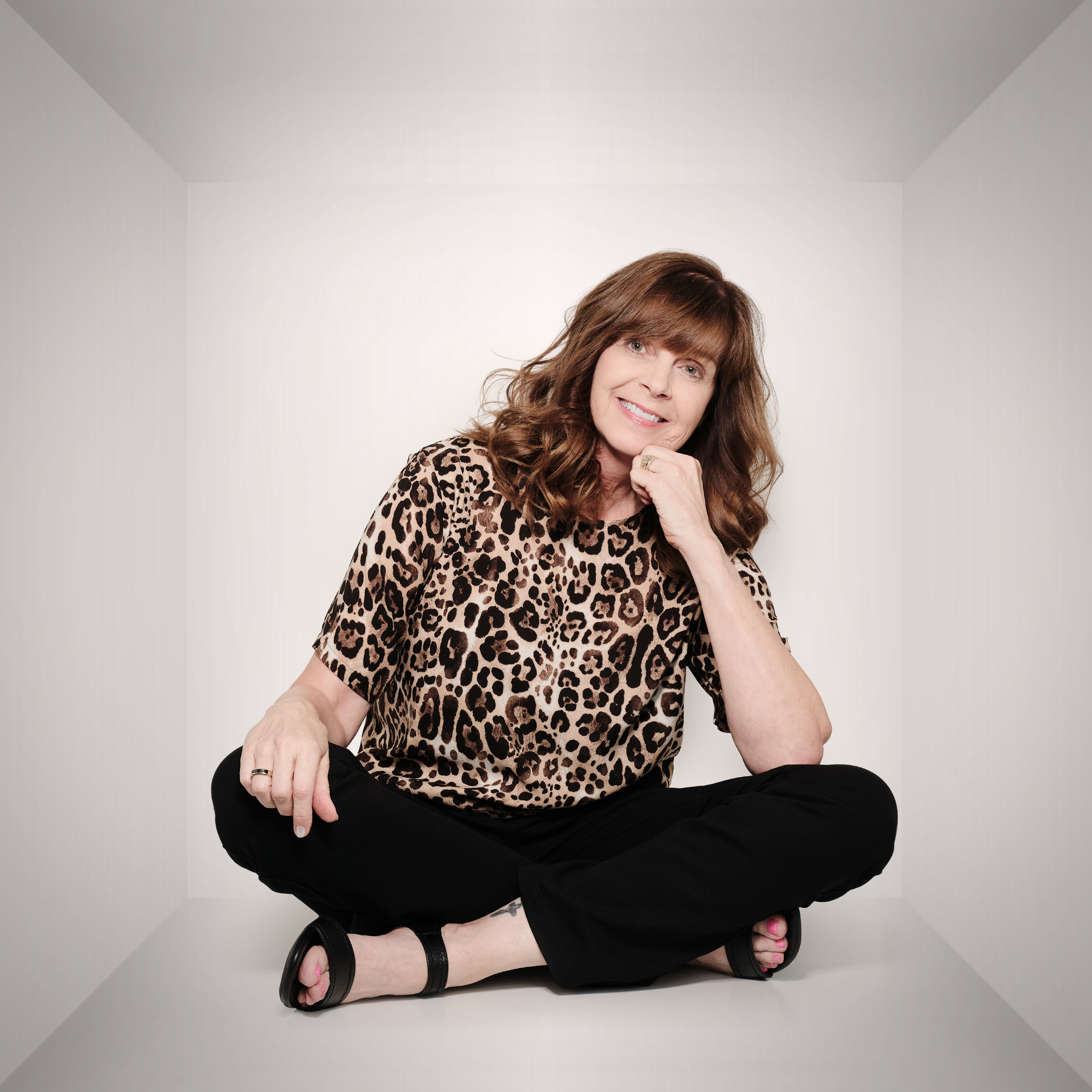 Jennifer sitting and smiling with her chin resting on her fist