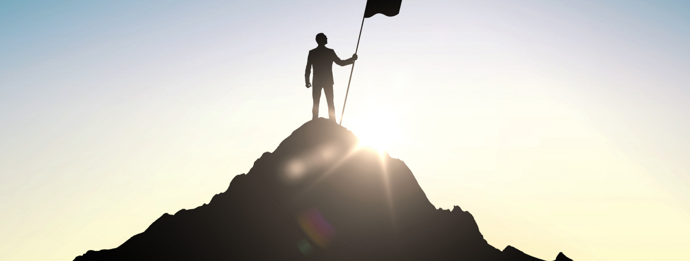 man on mountain with flag