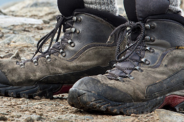 High-resolution zoomed in image showing design detail of a print ad created By FabCom featuring a man wearing brown leather hiking books.