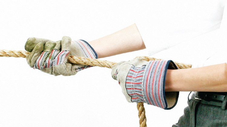 Zoomed in image by FabCom of a person wearing gloves pulling a rope.