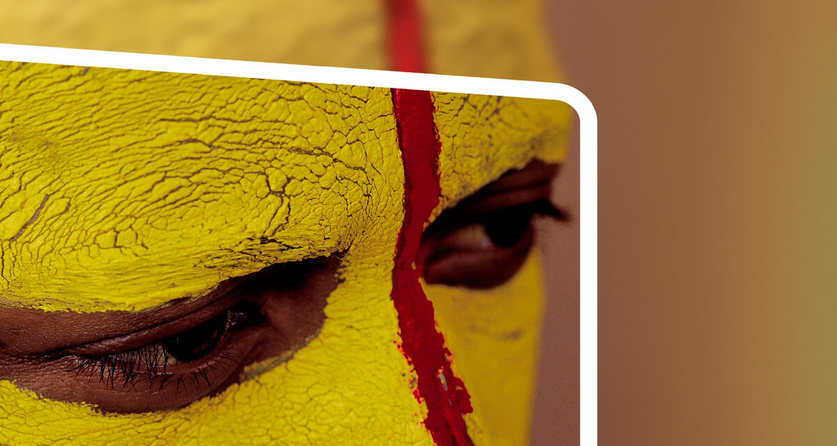 High-resolution close-up image showing the intricate detail of a direct mail piece FabCom designed. Image shows a primitive man with his face painted yellow and red.