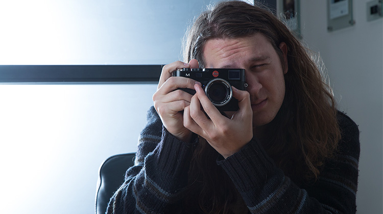 FabCom Videographer and Editor Tyler taking a photo with his Leica M sporting a Zeiss 50mm lens